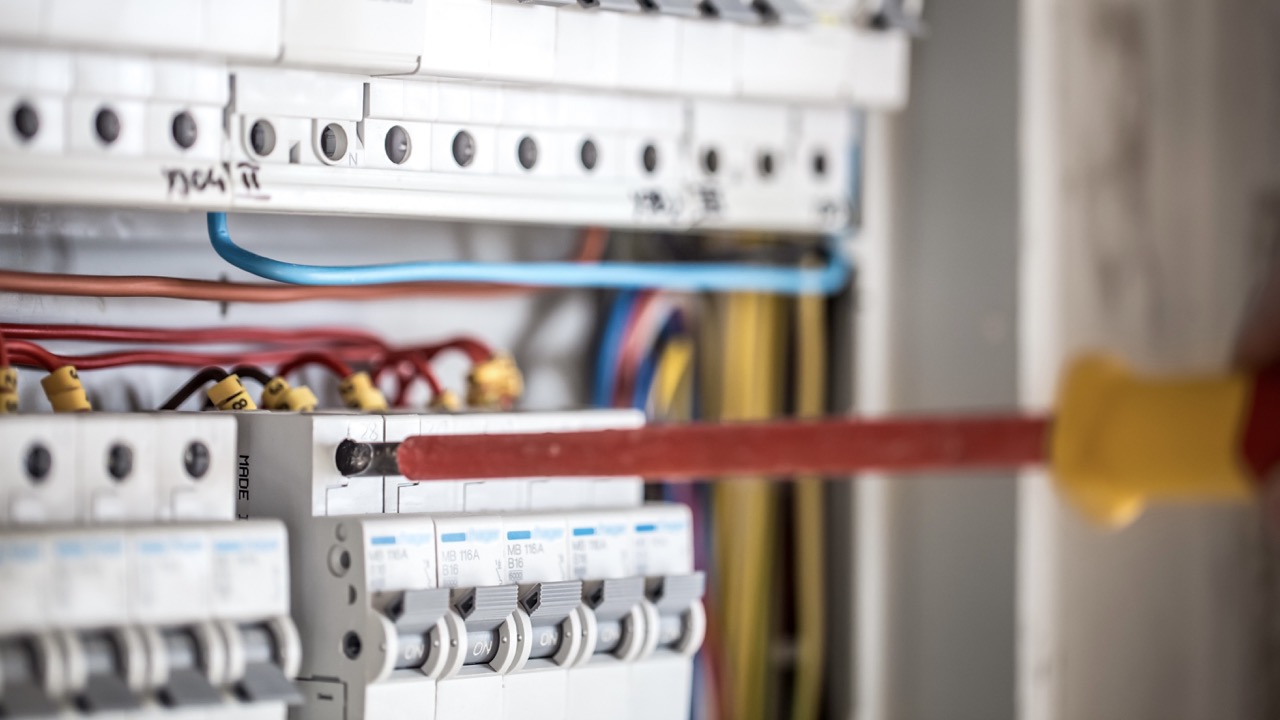 Man, an electrical technician working in a switchboard with fuses. Installation and connection of electrical equipment. Professional with tools in hand. concept of complex work, space for text.